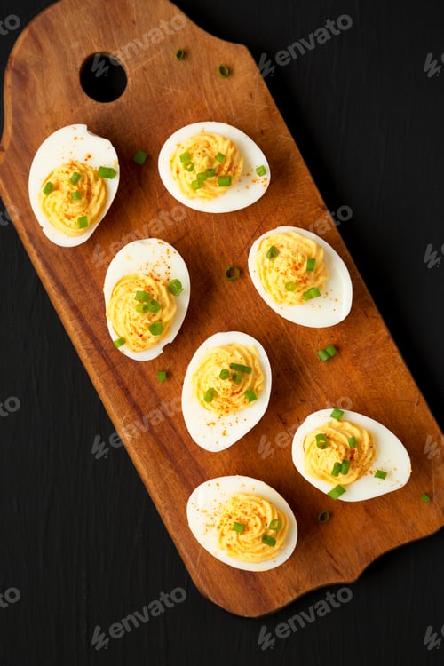 Preview: Homemade Deviled Eggs With Chives On A Rustic Wooden Board On A Black Surface, Top View. Flat Lay