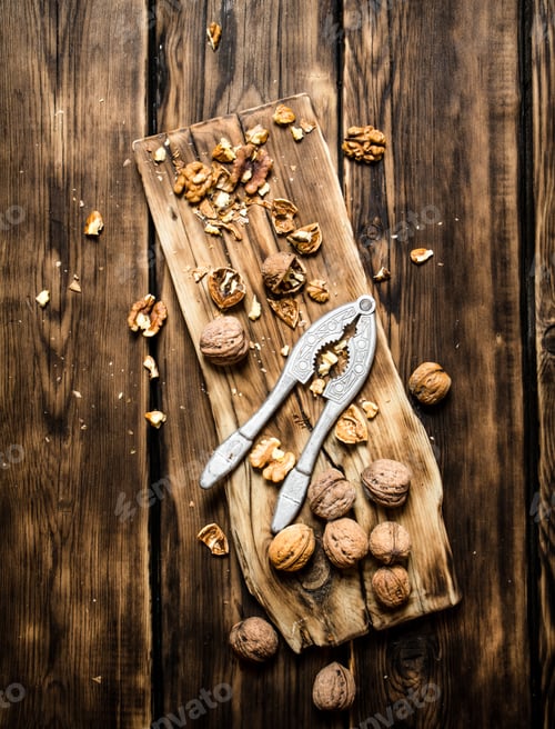 Preview: Walnuts With Nutcracker On The Board. On A Wooden Table.