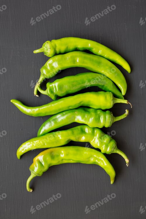 Preview: Green Chili Peppers On Black Surface, Top View. Flat Lay, From Above, Overhead. Close-Up.