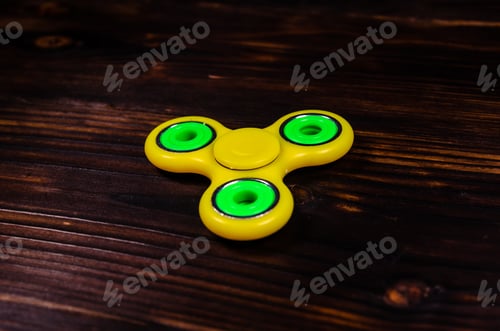 Preview: Yellow Fidget Spinner On Rustic Wooden Desk