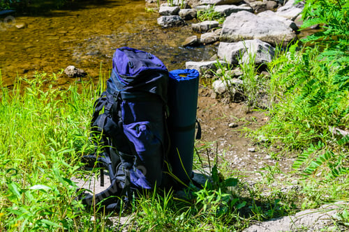 Preview: Touristic Backpack On A Bank Of The River In Forest