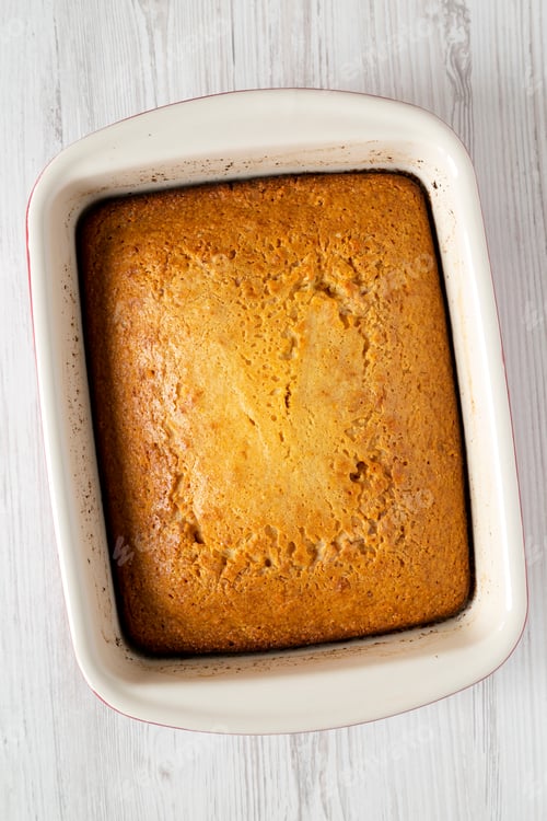 Preview: Homemade Sweet Cornbread In A Dish Over White Wooden Background, Top View. Flat Lay, Overhead, From