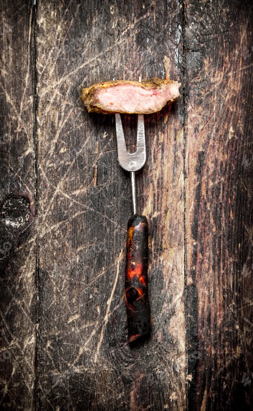 Preview: Meat Grill. A Piece Of Pork Grilled On A Fork . On The Old Wooden Table.