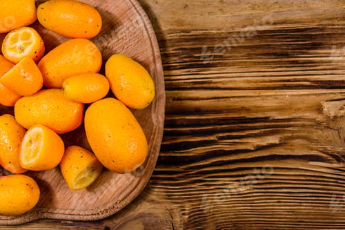 Preview: Cutting Board With Kumquat Fruits On A Wooden Table. Top View