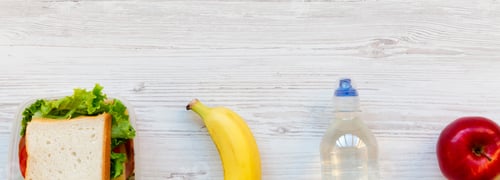 Preview: Healthy School Lunch Box With Sandwich, Fruits And Bottle Of Water On White Wooden Surface, Top