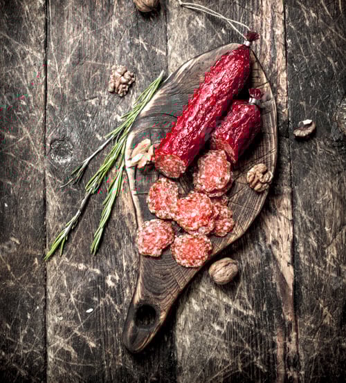 Preview: Salami With Herbs And Spices On A Board. On A Wooden Background.