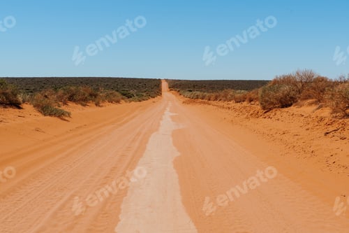 Preview: Dusty Australian Outback Red Road. Remote Track In Australian Bushland Against Clear Blue Sky. Red