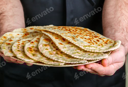 Preview: Delicious Gourmet Flat Bread Kutabs With Herbs And Cheese On A Plate In The Hands Of The Chef