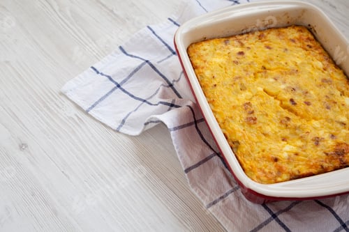 Preview: Home-Baked Cheesy Amish Breakfast Casserole On A White Wooden Surface, Low Angle View. Copy Space.