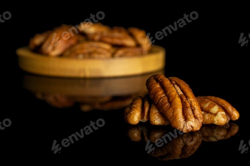 Preview: Lot Of Whole Dry Brown Pecan Nut On Bamboo Coaster Isolated On Black Glass
