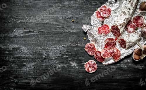 Preview: Spicy Salami With Spices On The Foil. On A Black Chalkboard.