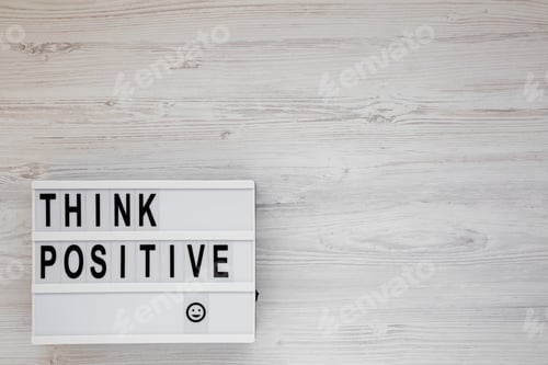 Preview: 'Think Positive' Words On A Lightbox On A White Wooden Surface, Top View. Overhead, From Above
