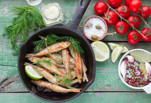 Preview: Fried Small Fish. Fried Smelt In The Pan On The Table With A Sauce, Lime, Tomatoes, Dill And Garlic