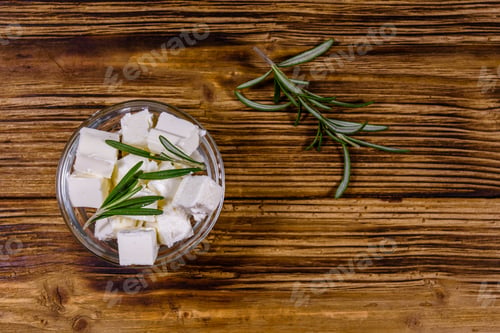 Preview: Chopped Feta Cheese And Rosemary In Glass Bowl On Wooden Table. Top View