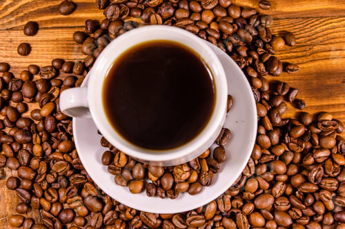 Preview: Cup Of Hot Coffee And Scattered Coffee Beans On Rustic Wooden Table. Top View