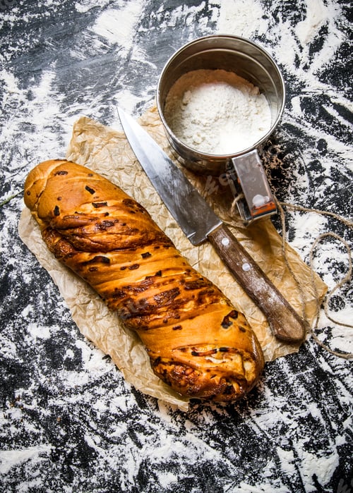Preview: Ciabatta With A Knife On Paper. On The Board With Flour. Top View