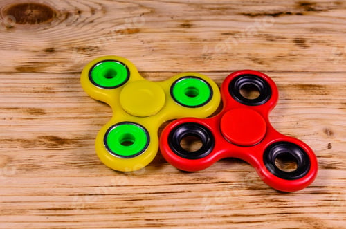 Preview: Yellow And Red Fidget Spinners On Rustic Wooden Desk