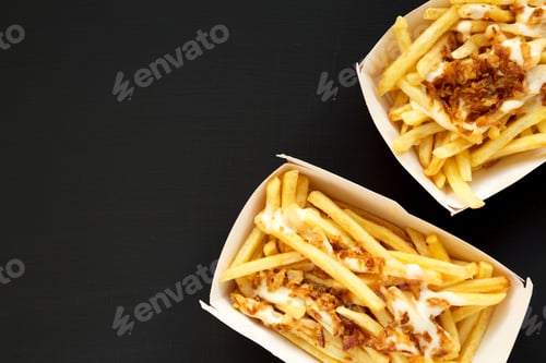 Preview: French Fries With Cheese Sauce And Fried Onion In Paper Boxes On A Black Surface, Top View. Flat