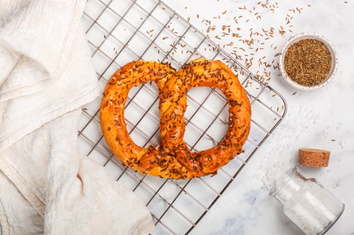 Preview: Freshly Baked Pretzel With Coarse Salt And Cumin. Gourmet Snacks And Ingredients At The Table