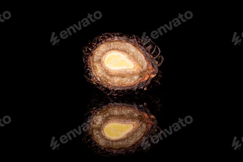 Preview: One Half Of Old Brown Rambutan Isolated On Black Glass