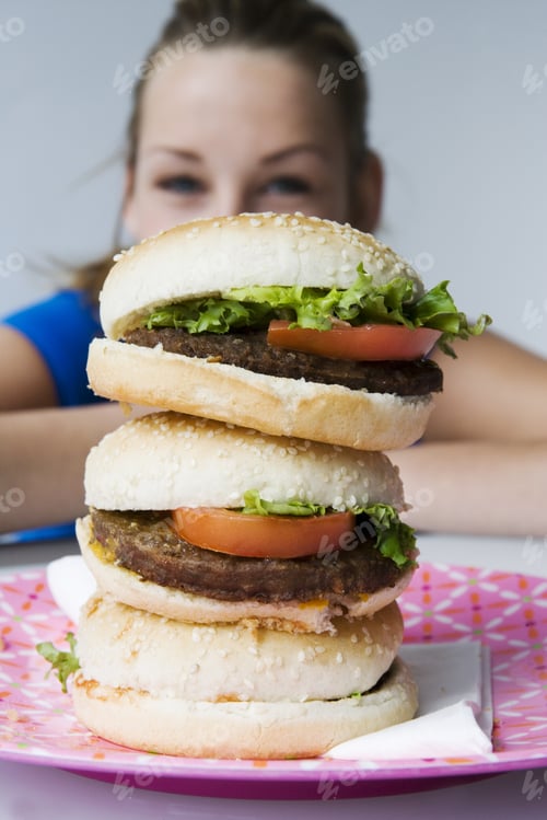 Preview: Close-Up Of Hamburgers With Teenage Girl In Background
