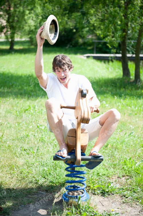 Preview: Young Man Riding Child'S Spring Ride In Park