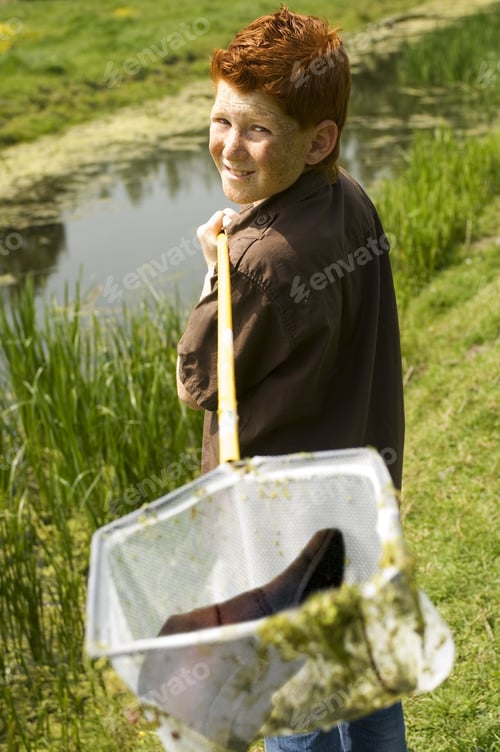 Preview: Young Boy Holding Net With Shoe Next To Water