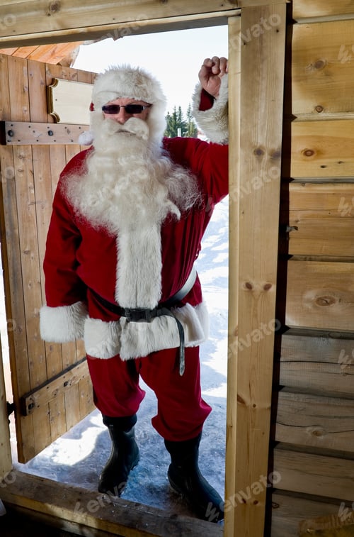 Preview: Santa Claus Standing In The Doorway Of A Log Cabin Wearing Sunglasses