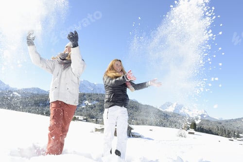 Preview: Young Woman And Teenage Friend Throwing Snow On Mountain