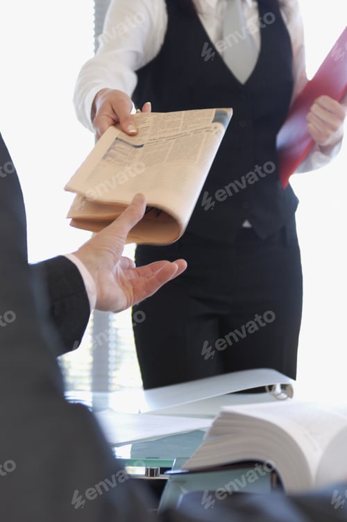Preview: Businesswoman Handing Newspaper To Businessman