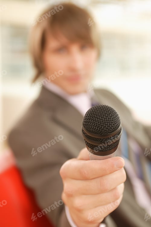 Preview: Young Businessman Holding Out A Microphone