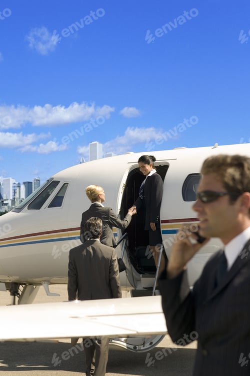 Preview: Businessman Using Cell Phone Next To Airplane On Tarmac