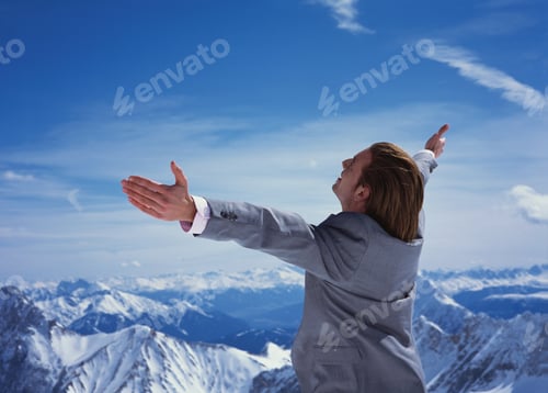 Preview: Businessman Standing With Arms Outstretched Overlooking Mountains