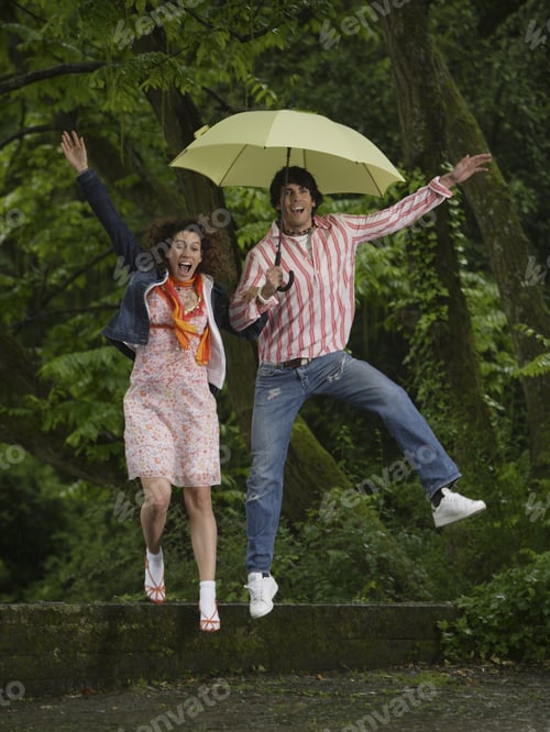 Preview: Couple Jumping With Umbrella Outdoors