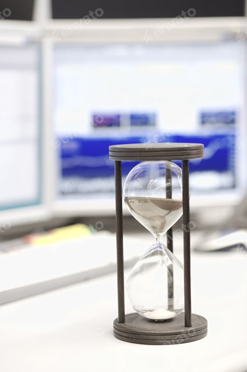 Preview: Hourglass On Desk In Front Of Computer Monitor