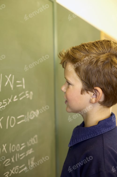 Preview: View Of Young Boy At Chalkboard Looking At Math Problem