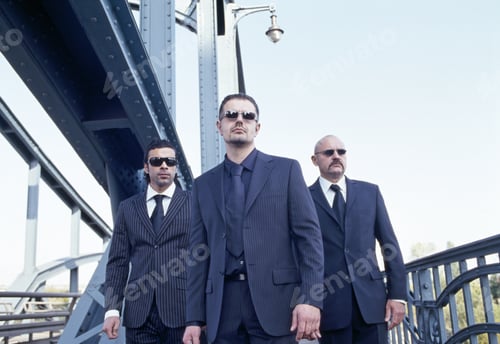 Preview: Three Men In Business Suits Walking On Bridge