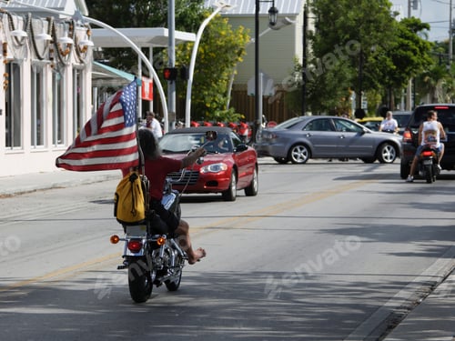 Preview: Barefoot Biker Riding On Street With American Flag, Key West, Florida, United States