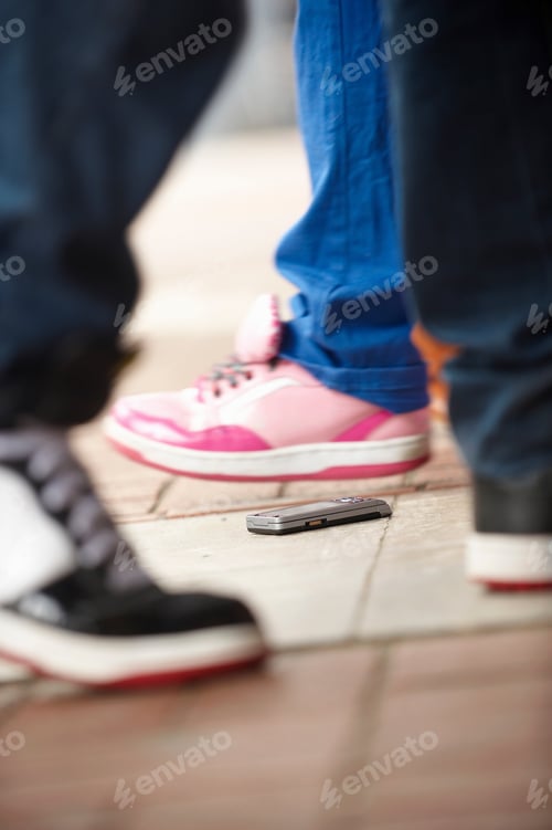 Preview: A Mobile Phone Lying On The Ground, Surrounded By Feet