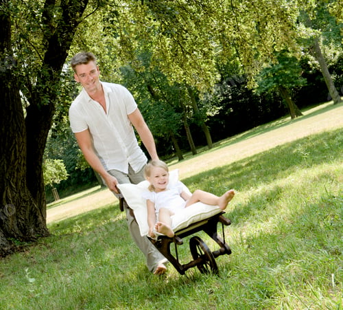 Preview: Father Pushing Young Daughter In Wheelbarrow In Park