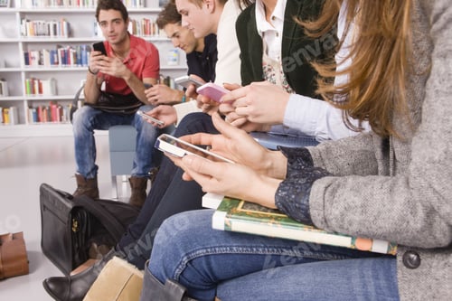 Preview: Young Students Texting On Cell Phones In Library
