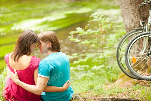 Preview: Young Affectionate Couple Sitting Near River