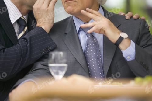 Preview: Businessman Whispering Into Other Businessman’S Ear At Lunch