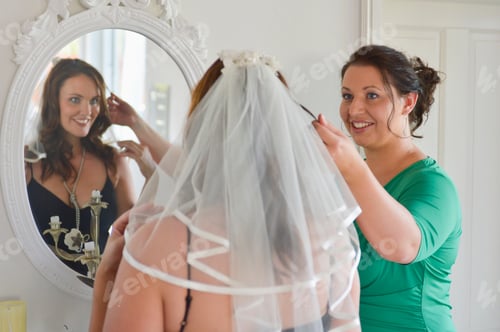 Preview: Mid Adult Woman Trying On Wedding Veil With Friend