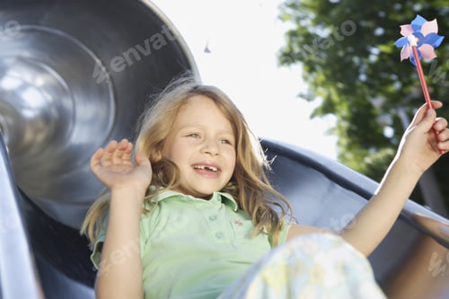 Preview: Close Up Of Girl Sliding Down Slide With Pinwheel