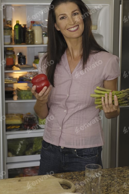 Preview: Woman Next To Refrigerator Holding Vegetables