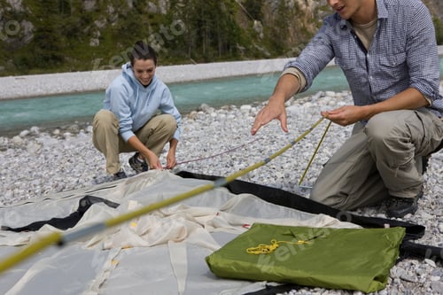 Preview: Young Couple Putting Up Camping Tent Near Stream