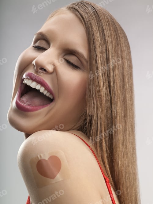 Preview: Young Happy Woman With Heart Shaped Patch On Shoulder, Studio Shot