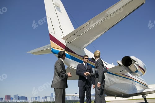 Preview: Low Angle View Of Businessman An Businesswoman Shaking Hands Next To Airplane