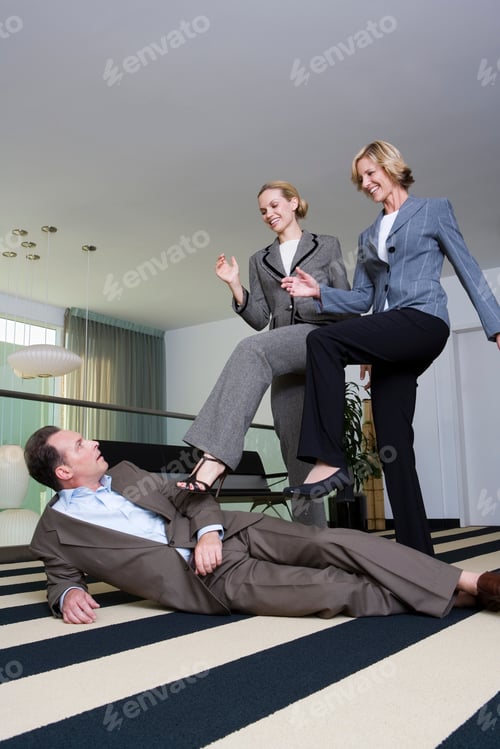 Preview: Two Businesswomen Standing Over Businessman On Floor